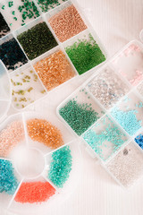 colored beads in transparent plastic boxes on a wooden table