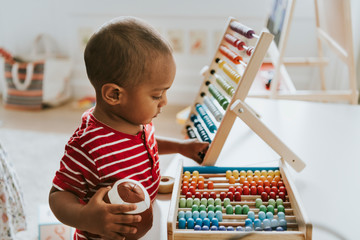 Kid playing with a colorful wooden abacus - obrazy, fototapety, plakaty