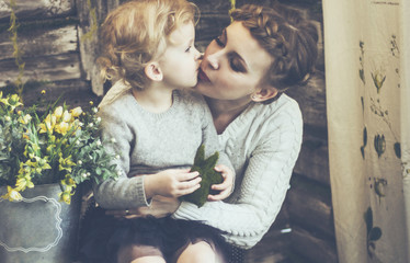 concept of motherhood:loving mother kisses his little daughter