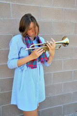 Female jazz trumpet player blowing her horn outside.