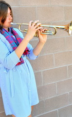 Female jazz trumpet player blowing her horn outside.