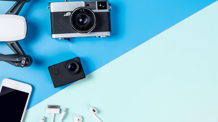 Hi tech travel gadget and accessories on blue and pink copy space with drone action camera