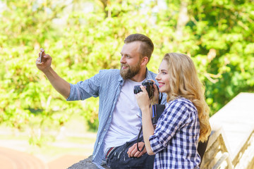 Man and woman taking photos with a camera and a smartphone.