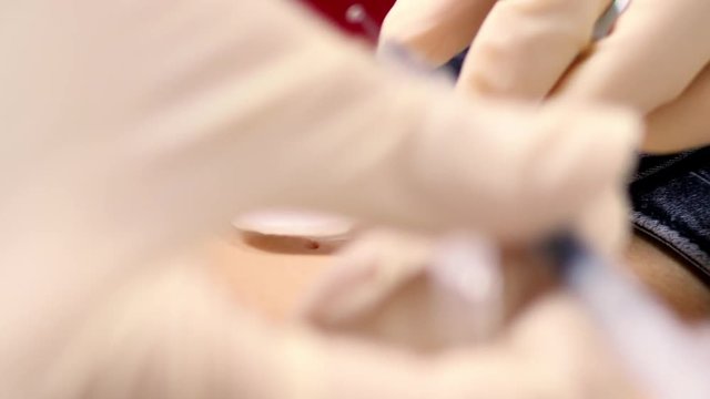 slow motion close view professional master hands in gloves doing procedure on client belly for navel piercing