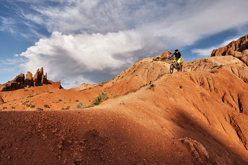 Cyclist riding a mountain bike downhill style in a canyon "Skazka" that looks like a Martian landscape. Issyk-Kul, Kyrgyzstan.