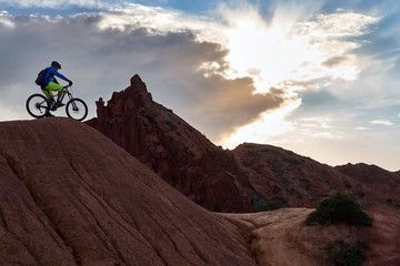 Cyclist riding a mountain bike downhill style in a canyon "Skazka" that looks like a Martian landscape. Issyk-Kul, Kyrgyzstan.