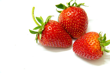 Three strawberries close up on white background.