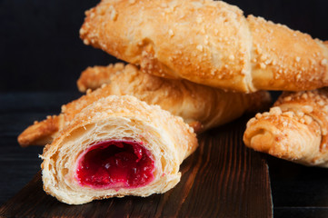 Croissants with raspberries on wooden cutting board.