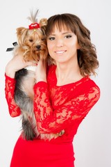 portrait of a young beautiful woman with a yorkshire terrier in her arms in a photo studio