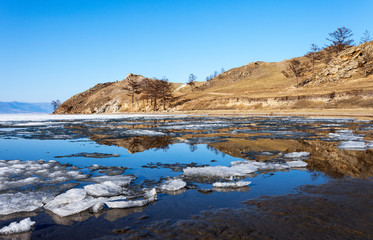 Spring sunny day on the shore of Lake Baikal. Ice floes are melting on the shores of the Kurkutsky Bay of the Small Sea