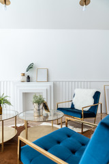 Cozy living room corner with gold and blue velvet fabric armchair and gold mirror coffee table in modern classic style with natural light setting scene / studio shot / interior design decoration