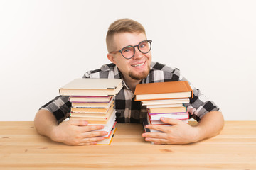 People, knowledge and education concept - smiling student man sitting at the table with books. He...