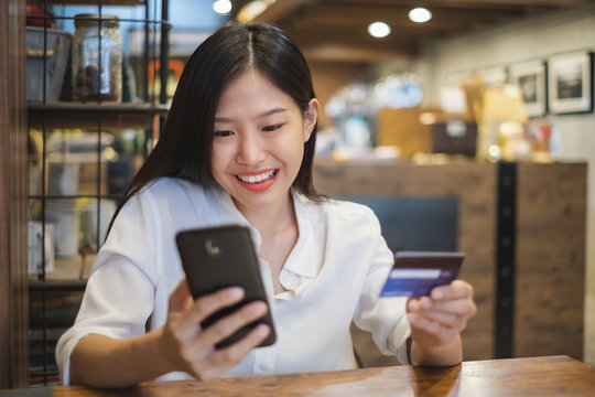 Young beautiful asian woman using smart phone and credit card for shopping online in coffee shop cafe