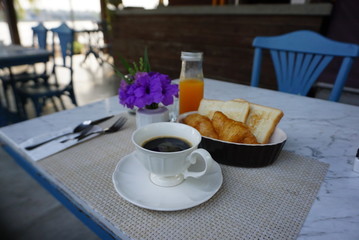 Black hot coffee serving in white vintage cup on the dining mat serving for breakfast with blue chair background