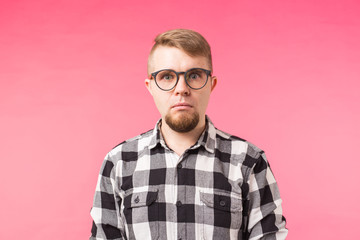 Emotions and people concept - Close up of a shocked young man dressed in plaid shirt over pink background