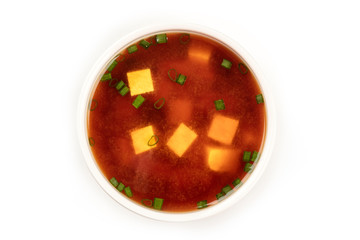 A bowl of miso soup with tofu and scallions, shot from above on a white background with a place for text
