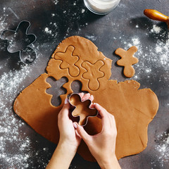 Flat lay christmas food concept Woman cooking gingerbread man cookies Christmas dark background top view Xmas dessert