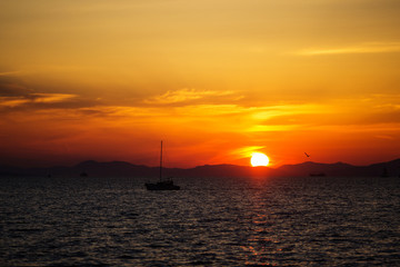 Beautiful bright sunset on the sea. A lone boat and yacht drift in the background of the sunset.