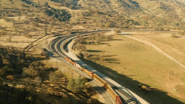 The aerial camera shoots a train going in to the south entrance of the rail loop from 150 feet above the tracks. The aerial camera follows the trail rolling towards the crisscross section of the loop.