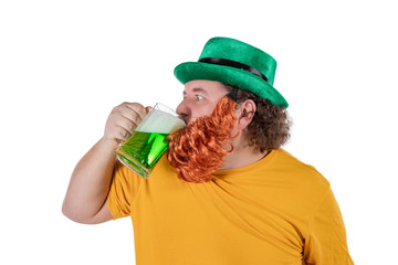 A smiling happy fat man in a leprechaun hat with green beer at studio. He celebrates St. Patrick