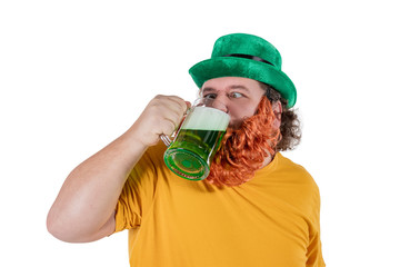 A smiling happy fat man in a leprechaun hat with green beer at studio. He celebrates St. Patrick