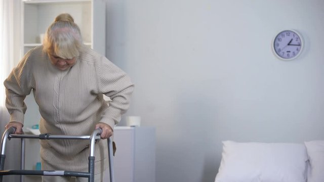 Old lady learning to walk with frame, rehabilitation after hip joint replacement