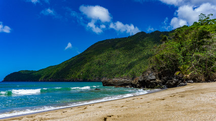 Fototapeta na wymiar Ein tropischer Strand mit Bergen und Felsen in der Karibik Punta Cana, Atlantik, nördlich des Äquators