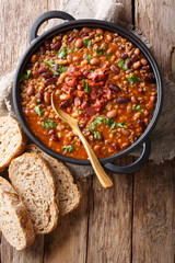 Delicious cowboy stew of beans with ground beef, bacon in a spicy sauce closeup in a bowl. Vertical...