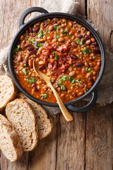 Delicious cowboy stew of beans with ground beef, bacon in a spicy sauce closeup in a bowl. Vertical top view