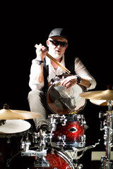 Fototapeta premium Drummer with a drumsticks in his hands sits behind drum kit on the black background