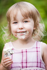 smiling little girl with soiled face and ice cream in the hand
