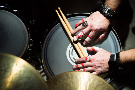 Hands of a musician with drumsticks lie on the drum
