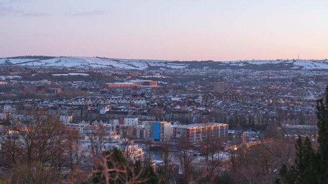 Sunset over winter city scenic, with snowy hilltops, Bristol UK time lapse