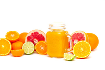Freshly blended yellow and orange fruit smoothie in glass jar. Glass jar mugs with orange health smoothie, lime, grapefruit, lemon, tangerine. Selective focus. Copy space. Vegetarian food concept.  