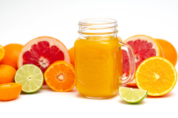 Freshly blended yellow and orange fruit smoothie in glass jar. Glass jar mugs with orange health smoothie, lime, grapefruit, lemon, tangerine. Selective focus. Copy space. Vegetarian food concept.  