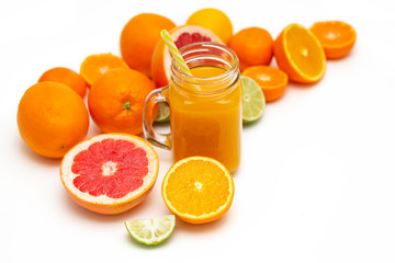 Freshly blended yellow and orange fruit smoothie in glass jar. Glass jar mugs with orange health smoothie, lime, grapefruit, lemon, tangerine. Selective focus. Copy space. Vegetarian food concept.  
