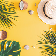 Summer composition. Tropical palm leaves, hat, coconut on pastel yellow background. Summer concept....