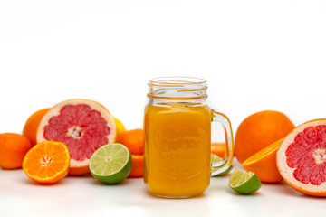 Freshly blended yellow and orange fruit smoothie in glass jar. Glass jar mugs with orange health smoothie, lime, grapefruit, lemon, tangerine. Selective focus. Copy space. Vegetarian food concept.  