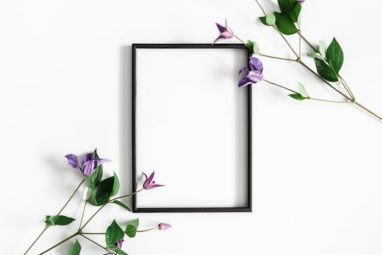 Flowers composition. Purple flowers, photo frame on pastel gray background. Spring concept. Flat lay, top view, copy space