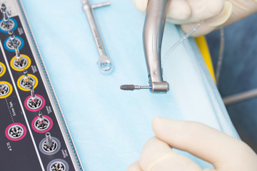 Close-up dental implant in the hands of a dentist. An implantation surgery is underway.