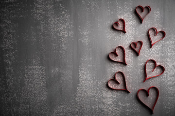 Valentines day and love concept. Many paper red hearts on gray wooden background.