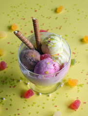 A cup of ice cream with rolled wafers. ice cream closeup, with yellow background.