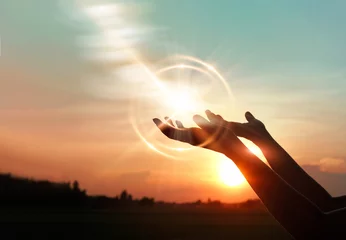 Foto op Plexiglas .Vrouwenhanden bidden voor zegen van god op zonsondergangachtergrond © ipopba