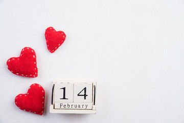 Valentines day and love concept. Handmade red heart and February 14 text on wooden block on white wooden background.