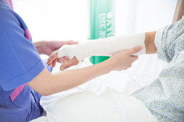Obraz na płótnie Canvas Closeup doctor bandaging arm of senior woman patient in hospital