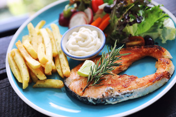 Roasted salmon steak , baked salmon with salad fresh vegetable pm wooden table