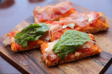 Pizza with parma ham salad rocket and parmesan on dark wooden background close up. Italian food