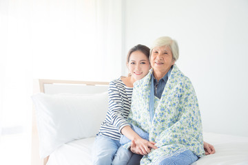 Beautiful asian daughter hugging her senior mother in bedroom at home