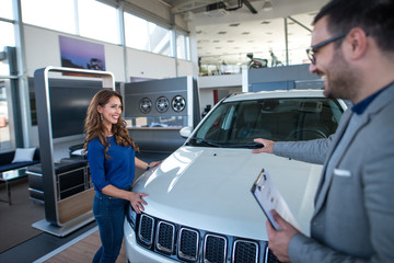 Car salesman presenting vehicle to the customer. Automobile dealership.