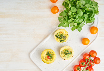 Egg muffins, paleo, keto diet. Omelet with spinach, vegetables, tomatoes baked in small molds, top view, copy space